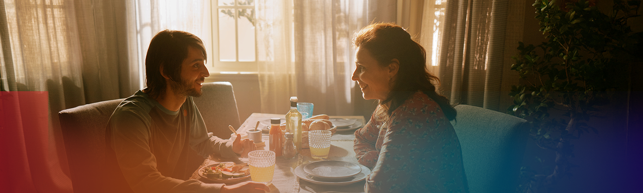 Young man and woman sitting at dining table smiling, banner