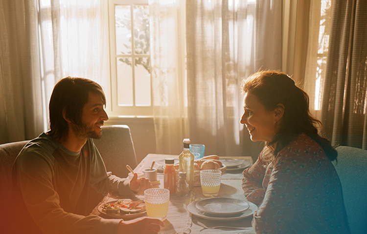 Young man and woman sitting at dining table smiling, banner