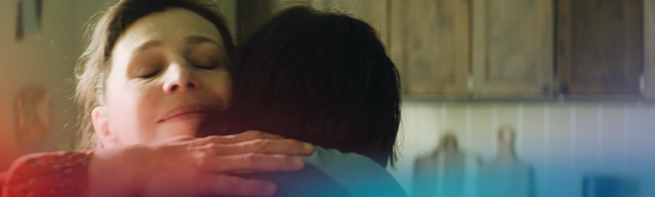 Woman smiling peacefully with eyes closed while hugging another person, expressing emotional warmth and connection.