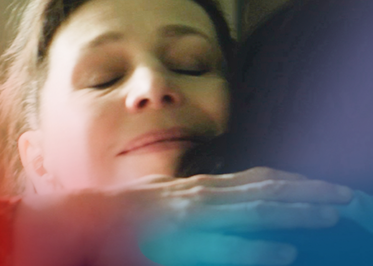 Woman smiling peacefully with eyes closed while hugging another person, expressing emotional warmth and connection.
