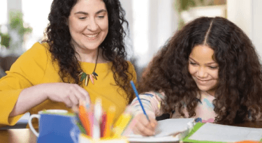 Mother and daughter working on crafts together at a table