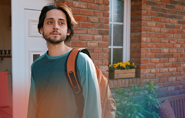 Young man outside a house with wind blowing through his hair