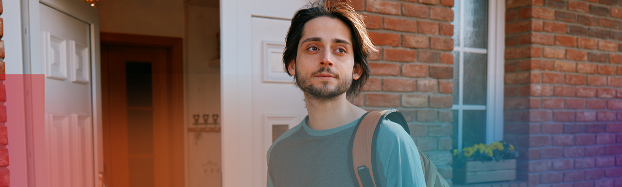 Young man outside a house with wind blowing through his hair