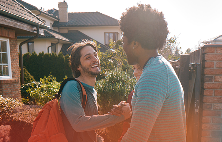 Young man greeting a man and woman with a smile